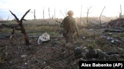 A Ukrainian soldier passes by the body of a dead Russian soldier in Andriyivka in the Donetsk region in September.