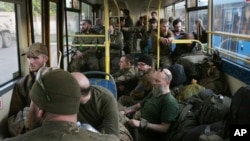 Украински војници седат во автобус откако беа евакуирани од челичарницата Азовстал во Мариупол, во близина на затвор во Ољонивка, на територијата под владата на Народната Република Доњецк, источна Украина, вторник, 17 мај 2022 година.