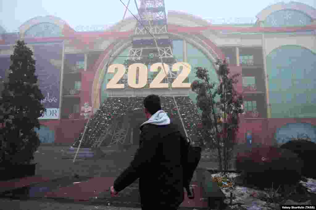 A man walks past the French House perfume store in Almaty on January 6. Security forces in Kazakhstan say they have killed dozens of anti-government rioters in Almaty. The authorities say 12 members of the security forces have been killed and 353 injured in the unrest, which was sparked by a doubling in the cost of liquefied petroleum gas (LPG).