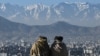 Members of the Taliban sit overlooking the Kabul city at the Wazir Akbar Khan hill in Kabul on January 20, 2022. 22potw03