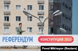 Конституцияға өзгертулер енгізуге байланысты референдум өтетіні жазылған баннер ілінген көпірмен өтіп бара жатқан адам. Алматы, 1 маусым, 2022 жыл.