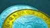 Kazakhstan. Name of the country on Kazakh coins in 100 and 50 tenge. The illustration is toned in the colors of the national flag. Transition to Latin alphabet. Macro