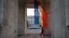 A woman walks under the Triumph Arch next to Moldovan flag on Stefan Cel Mare street in Chisinau. (file photo)