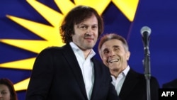 „ქართული ოცნების“ ლიდერები, ირაკლი კობახიძე და ბიძინა ივანიშვილი პარტიისა და ევროკავშირის დროშის ფონზე