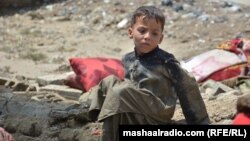 په خوست کې یو ماشوم په ورښتونو کې له خپل زیانمن شوي کور سره نېږدې ناست دی - د اګست شپږمې انځور.