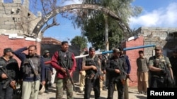 Policemen stand guard at a courthouse after an attack by suicide bombers in Charsadda on February 21.