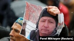 Человек держит фотографию Дулата Агадила —активиста, погибшего в СИЗО, — на акции памяти в его честь. Алматы, 27 февраля 2020 года.