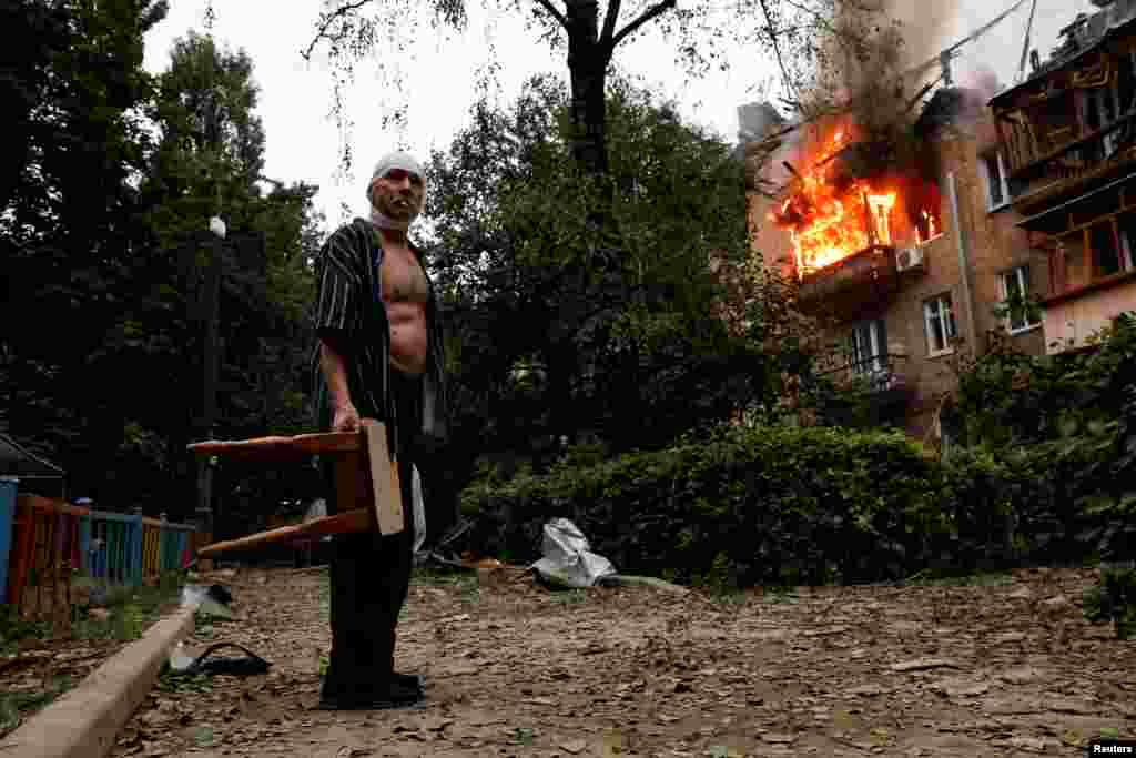 An injured resident stands outside his house, which was damaged during Russian missile and drone strikes on Kyiv.