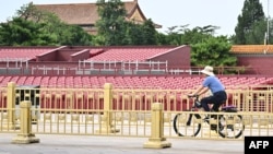 Muškarac vozi bicikl ispred štandova postavljenih na Trgu Tiananmen za vojnu paradu 3. septembra povodom 80. godišnjice pobjede nad Japanom i završetka Drugog svjetskog rata.