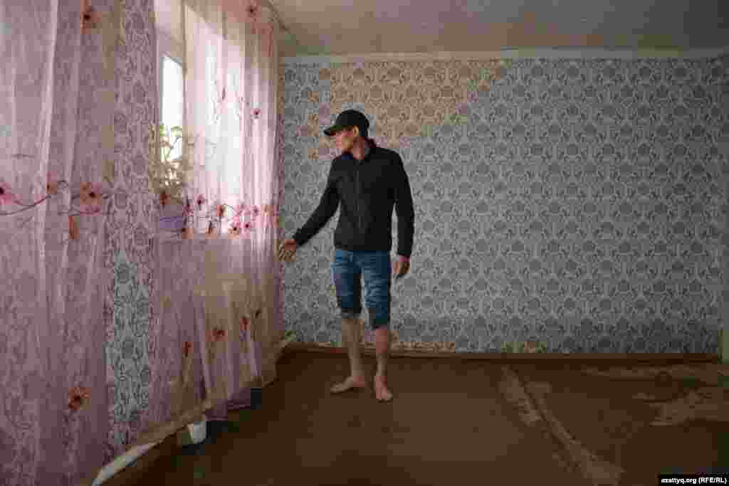 Житель села показывает свой дом, пострадавший из-за паводка. 